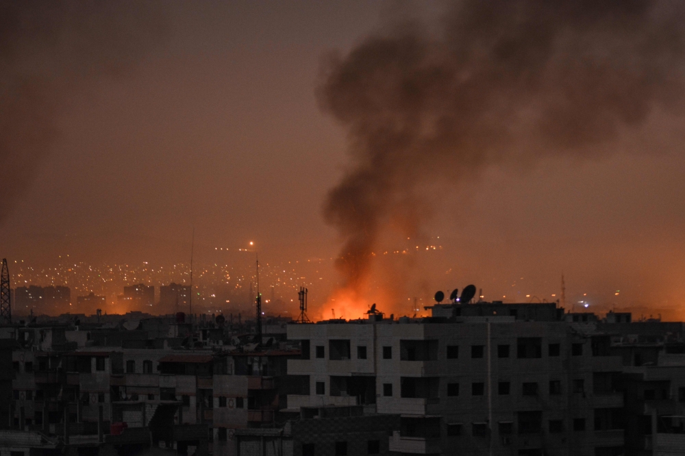 A picture taken late on April 28, 2018 shows smoke plumes rising from explosions in the skyline of a southern district of the Syrian capital Damascus, during regime strikes targeting the Islamic State group in the Palestinian camp of Yarmuk, and neighbour