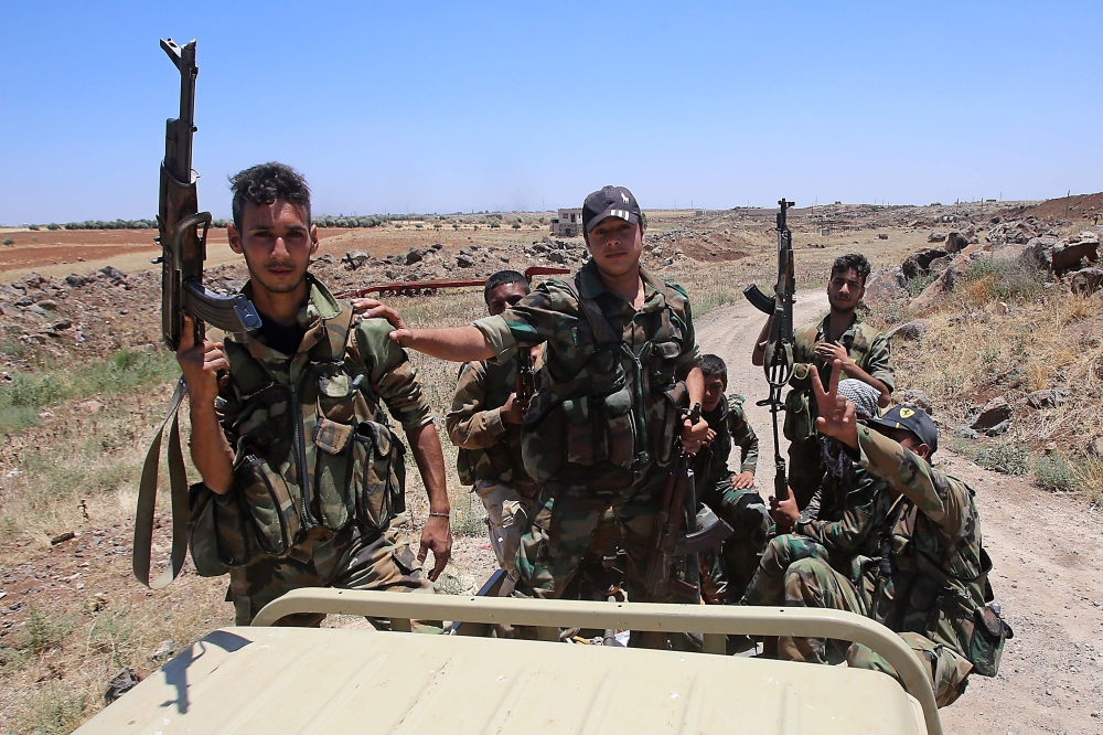 Syrian government forces' soldiers hold their weapons at the back of a pick-up truck during a government guided tour in the village of al-Sourah, province of Daraa, on June 29, 2018.  AFP / Youssef karwashan