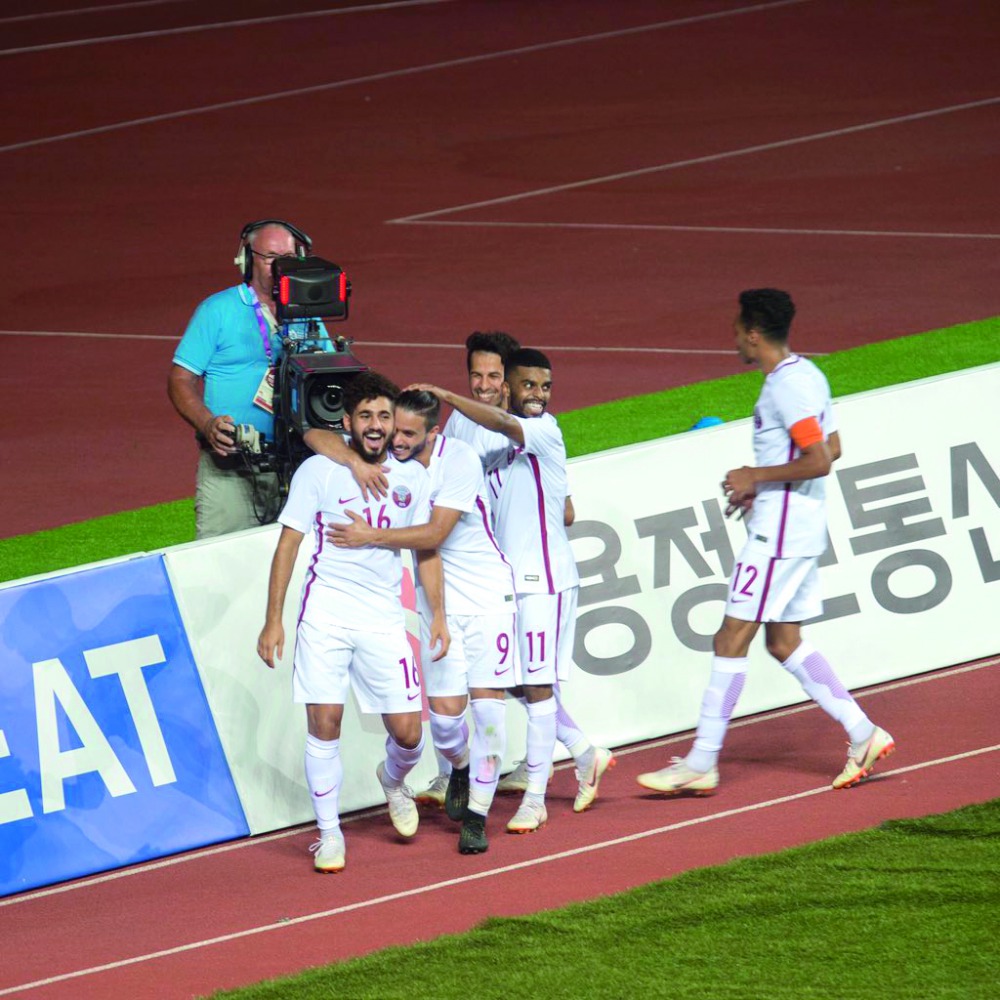 Qatari players celebrate after scoring a goal against Thailand during their opening match of the Asian Games at the Pakan Sari Stadium in Bogor, Indonesia yesterday. LEFT: Players vie for the ball possession during yesterday’s match.