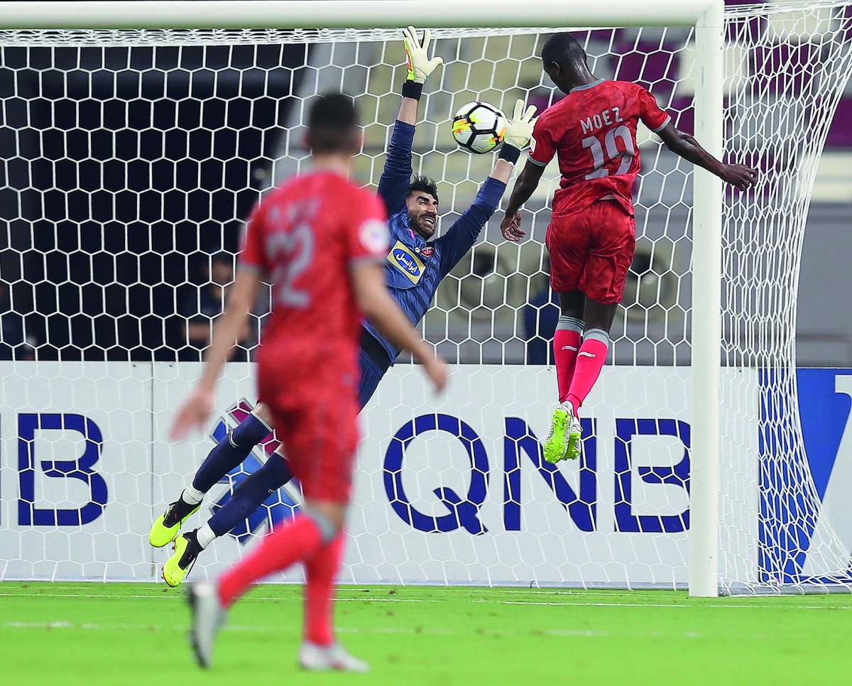 Al Duhail SC’s Qatari forward Almoez Ali heads a goal against Persepolis SC’s Iranian goalkeeper Alireza Beiranvand during the AFC Champions League football match at Khalifa International Stadium in Doha yesterday.
