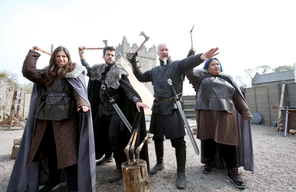 French Game of Thrones fans, Claire Pottier (L) and Hugo Chivard (2L), from Normandy, US fan Jocelyn Vadli (R) take part in axe throwing with Master of Arms Will van der Kells (2R) at the Castle Ward Estate in Strangford, northern Ireland, on April 17, 20