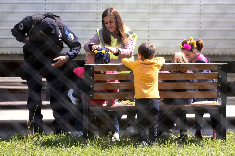 Kosovar children made crown of flowers with Kosovar police officers in the compound of the foreign detention center in the village of Vranidoll, Kosovo, on April 20, 2019. AFP / Armend NIMANI