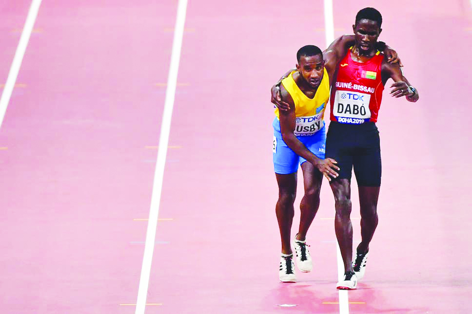 Guinea-Bissau’s Braima Suncar Dabo (right) helps Aruba’s Jonathan Busby to the finish line during the men’s 5,000m heats during the IAAF World Championships Doha 2019.