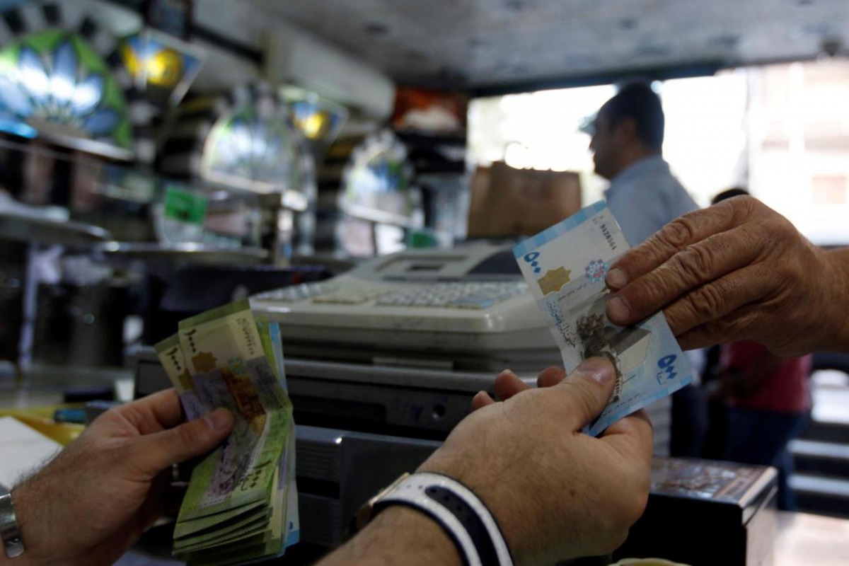 File photo : A cashier hands Syrian pounds to a customer inside a sweets shop in Damascus, Syria May 11, 2016. REUTERS/Omar Sanadiki