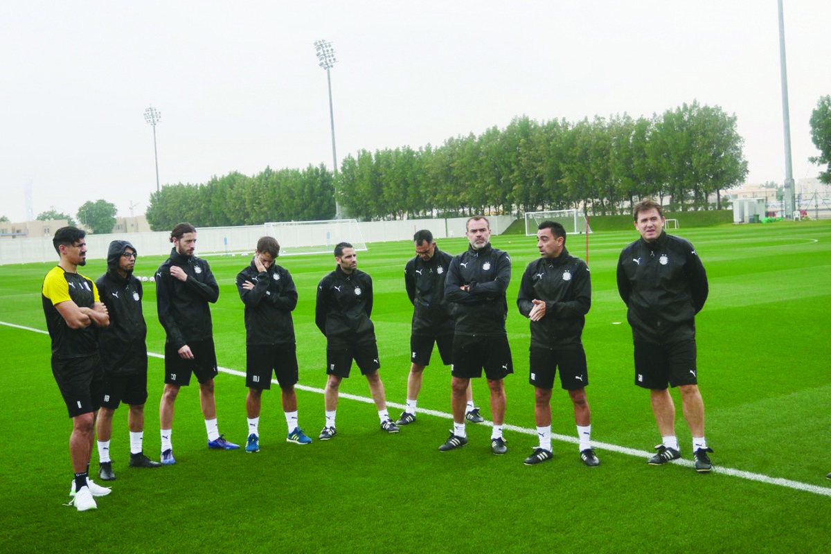 Coach Xavi (second right) speaks to players and officials during a training session at the Al Sadd training pitch yesterday.