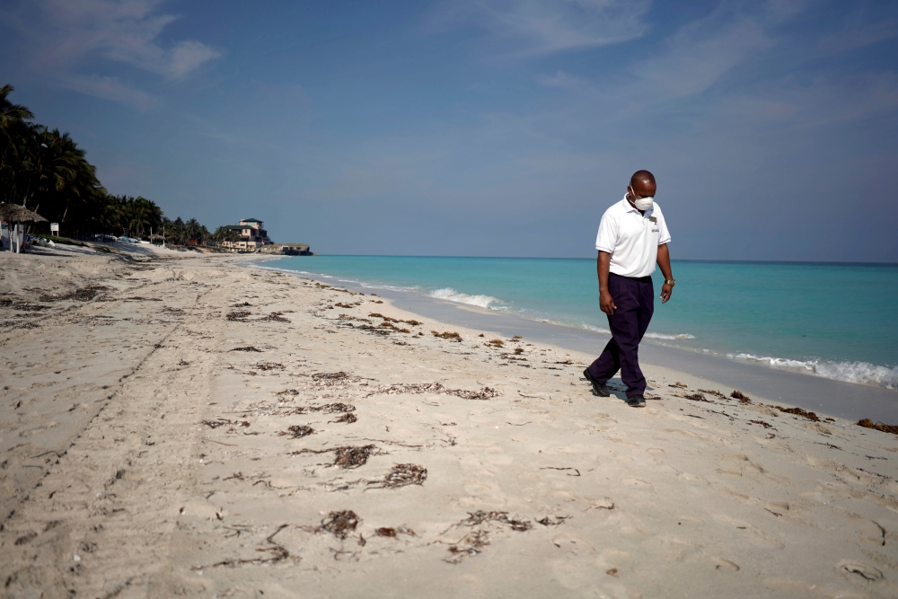 FILE PHOTO: A security agent wearing a protective mask walks on the beach amid concerns about the spread of the coronavirus disease (COVID-19), in Varadero, Cuba, April 10, 2020. Picture taken April 10, 2020. REUTERS/Alexandre Meneghini -/File Photo