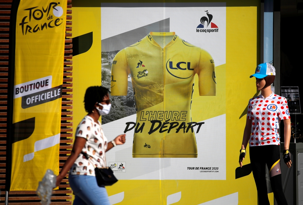 August 26, 2020 A person wearing a protective face mask walks past a merchandise store ahead of the Tour de France REUTERS/Stephane Mahe