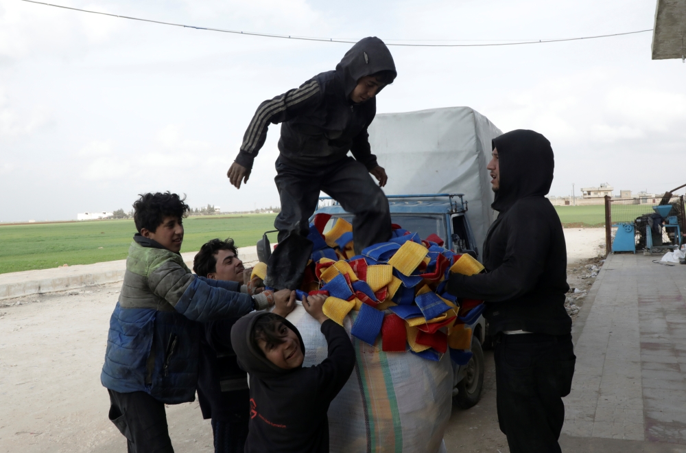 Mohammed Abu Rdan stands on a bag of dishcloths, in front of the cleaning products factory, in northern Aleppo, Syria March 11, 2021. Picture taken March 11, 2021. REUTERS/Mahmoud Hassano