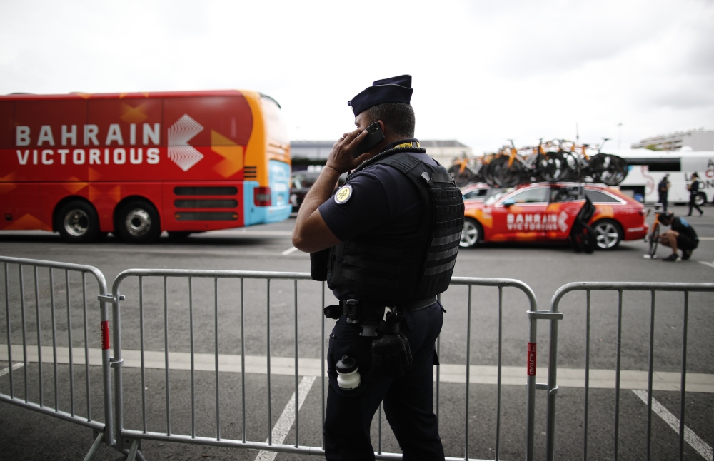 A police officer is pictured with the Bahrain Victorious team bus background after the Bahrain Victorious team bus and accommodation was searched by police yesterday (REUTERS/Benoit Tessier)