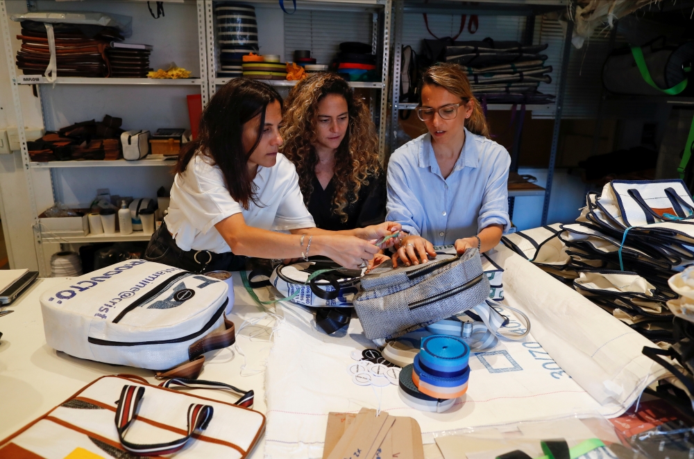 Sisters Carla, Ornella and Mora Basilotta, owners of the fashion firm Fracking Design discuss the design of a purse made with plastic sack used for holding sand in Vaca Muerta shale formation, in Buenos Aires, Argentina November 24, 2021. Picture taken November 24, 2021. REUTERS/Agustin Marcarian