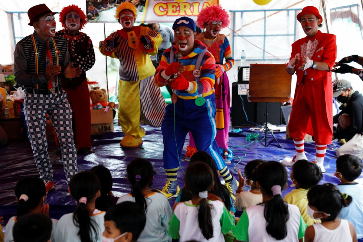 Dedy Rachmanto, 53, known as Dedy Delon who is the founder of a clowns' association called Aku Badut Indonesia or 'I Indonesia Clown', perform a show with other clowns to cheer the children who were affected by the eruption of Mount Semeru volcano, inside a temporary tent in Penanggal, Candipuro district, Lumajang, East Java province, Indonesia, December 9, 2021. REUTERS/Willy Kurniawan
