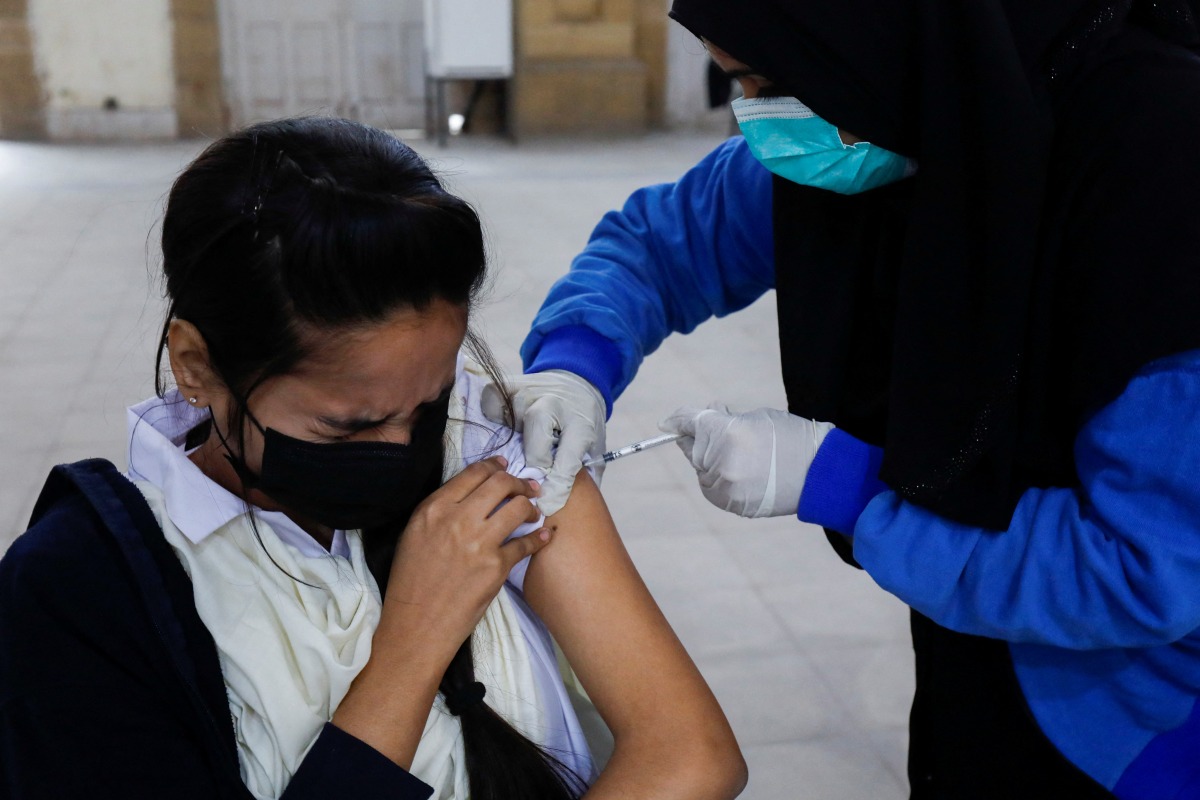 Student Fatima Zakir, 16, reacts as she receives her secound dose of coronavirus disease (COVID-19) vaccine at a vaccination centre in Karachi, Pakistan, January 4, 2022. REUTERS/Akhtar Soomro
