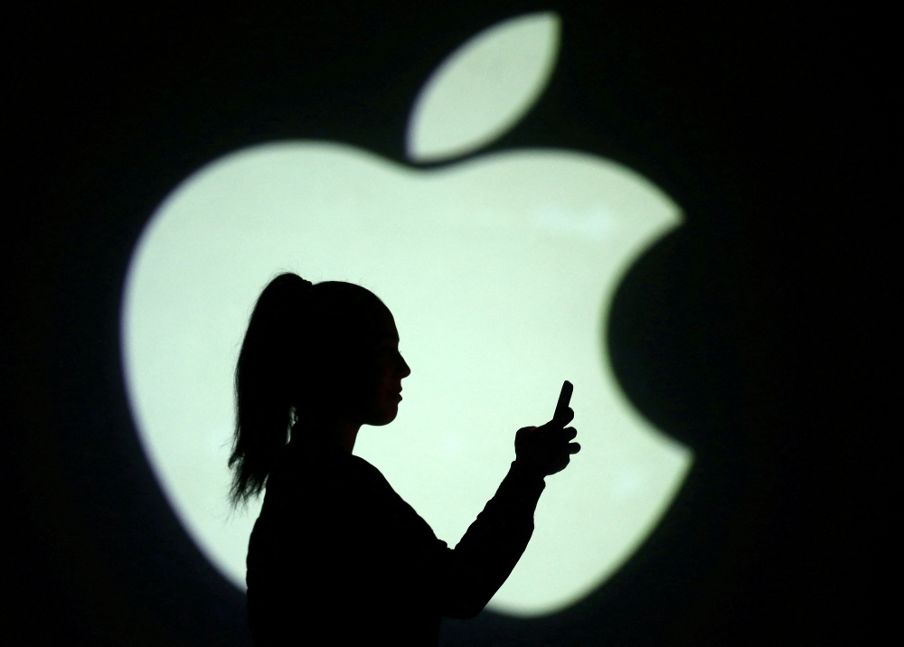 Silhouette of mobile user is seen next to a screen projection of Apple logo in this picture illustration taken March 28, 2018. REUTERS/Dado Ruvic/Illustration/File Photo