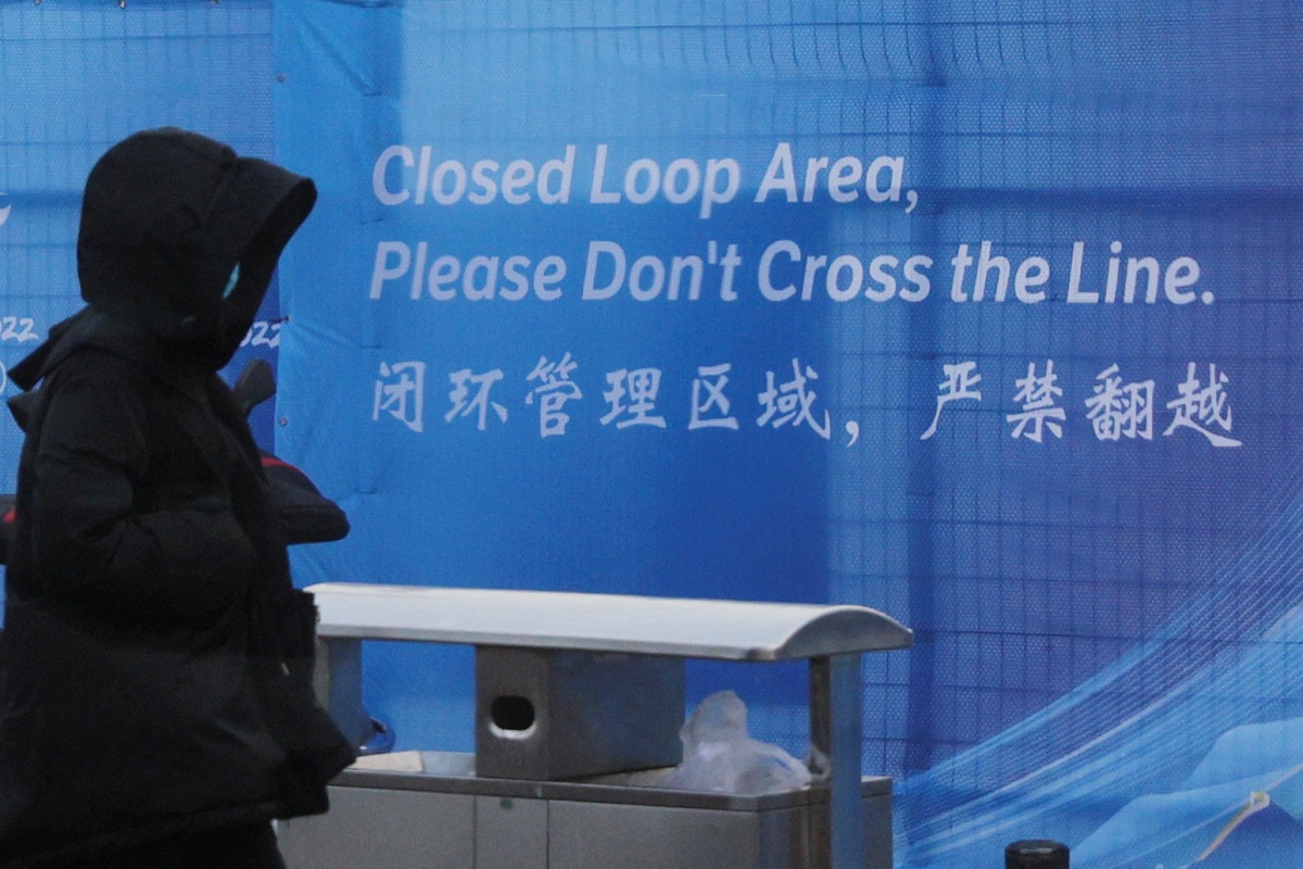 A pedestrian passes a sign marking the barrier of the 