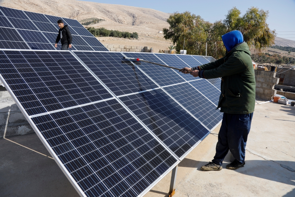 A worker cleans solar panels, which are one of the sustainable energy options that help olive farmers, in Mosul, Iraq February 2, 2022. Picture taken February 2, 2022. Reuters/Khalid al-Mousily