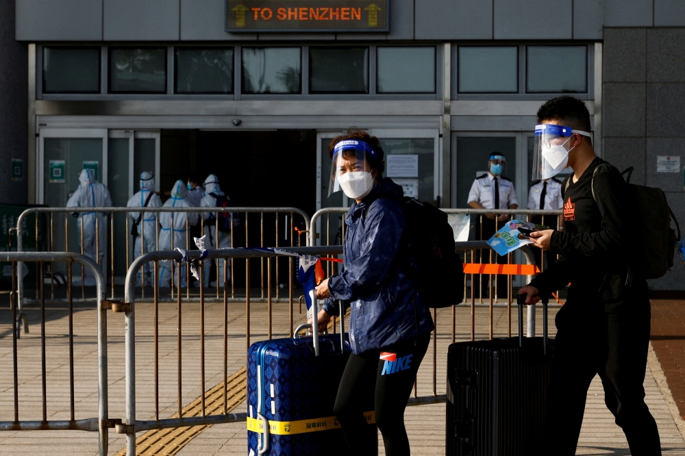 FILE PHOTO: Travellers wearing face mask and shield, walk at the China-Hong Kong border of Shenzhen Bay Port, during the coronavirus disease (COVID-19) pandemic in Hong Kong, China, March 14, 2022. REUTERS/Tyrone Siu