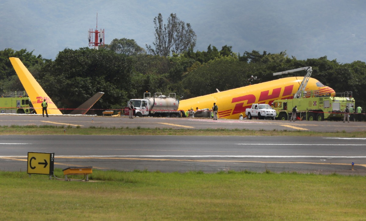 Firefighters work at the scene where a Boeing 757-200 cargo aircraft operated by DHL made an emergency landing before skidding off the runway and splitting, aviation authorities said, at the Juan Santamaria International Airport in Alajuela, Costa Rica April 7, 2022. REUTERS/Mayela Lopez
