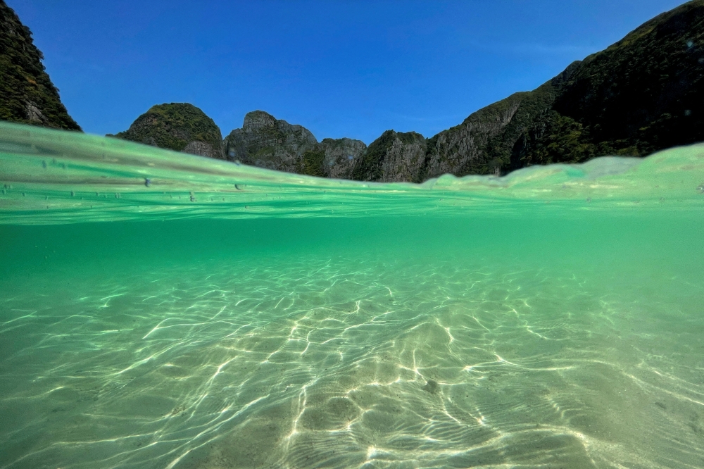 A partially underwater shot shows the waters at the beach of Maya Bay as Thailand reopens its world-famous beach after closing it for more than three years to allow its ecosystem to recover from the impact of overtourism, at Krabi province, Thailand, January 3, 2022. REUTERS/Jorge Silva/File Photo