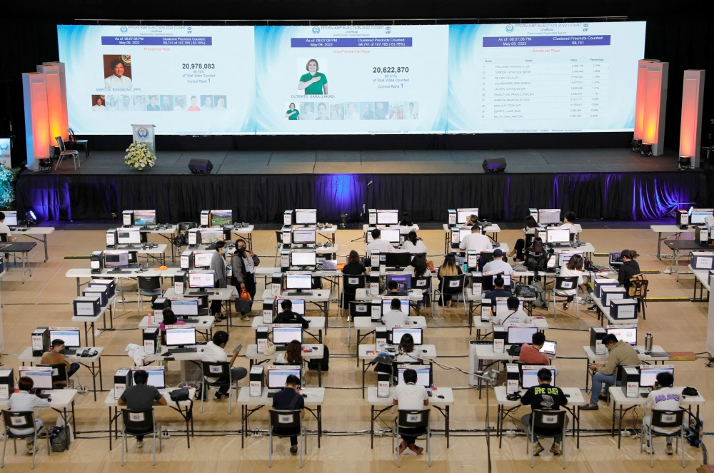 Staff members sit at computers as screens show an official quick-count of the national election at a command center of the Parish Pastoral Council for Responsible Voting (PPCRV), the election watchdog organization in Manila, Philippines, May 9, 2022. REUTERS/Willy Kurniawan