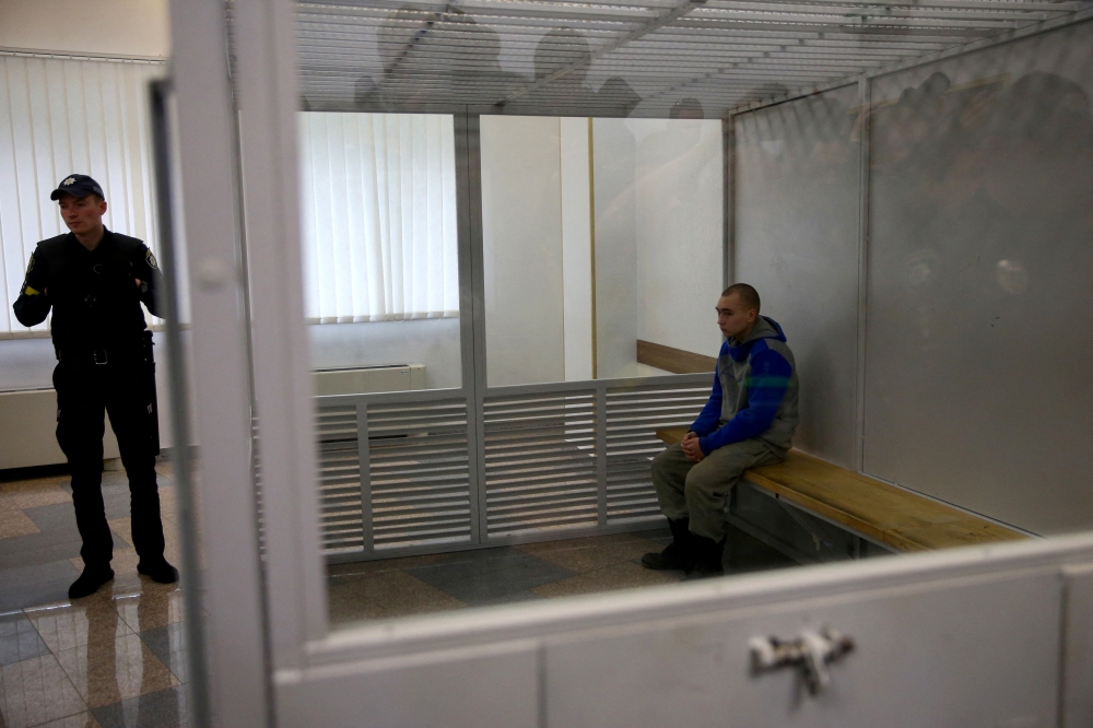 Russian soldier Vadim Shishimarin, 21, suspected of violations of the laws and norms of war, sits inside a cage during a court hearing, amid Russia's invasion of Ukraine, in Kyiv, Ukraine May 23, 2022. Reuters/Viacheslav Ratynskyi
