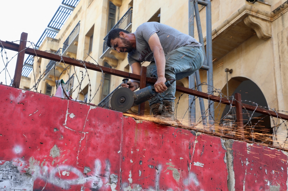 A worker uses a saw during the works to remove a concrete barrier blocking a street leading to the Parliament building, in Beirut, Lebanon May 23, 2022. REUTERS