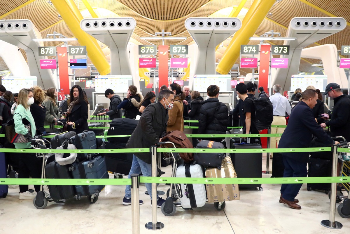 FILE PHOTO: Passengers wait for checking-in before boarding their flights to the U.S. at Madrid's Adolfo Suarez Barajas airport, Spain March 12, 2020. REUTERS/Sergio Perez/File Photo
