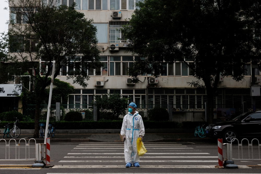 Medical worker in a protective suit crosses a street following a coronavirus disease (COVID-19) outbreak in Beijing, China, July 6, 2022. REUTERS/Thomas Peter