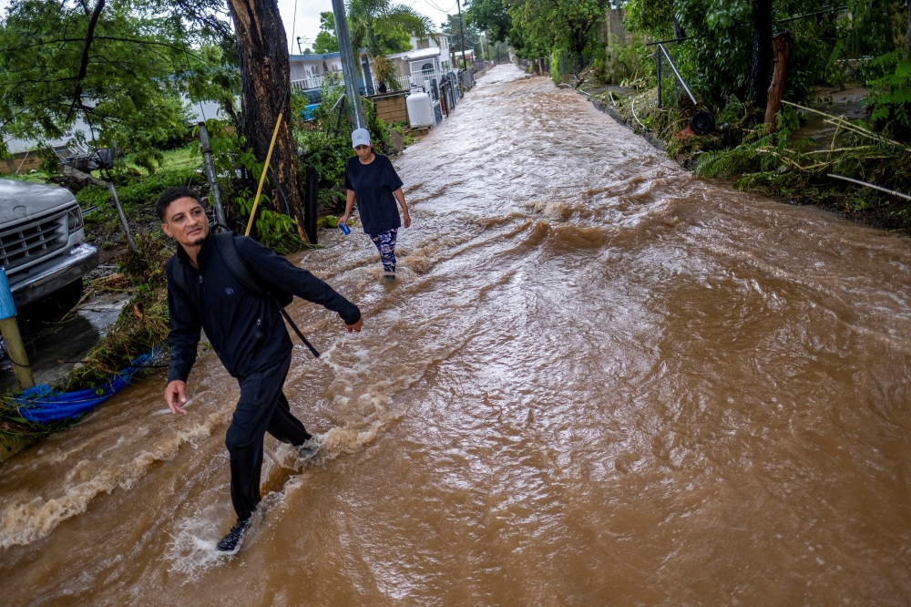 People wade through water on a flooded street in the aftermath of Hurricane Fiona in Salinas, Puerto Rico September 19, 2022. Reuters/Ricardo Arduengo