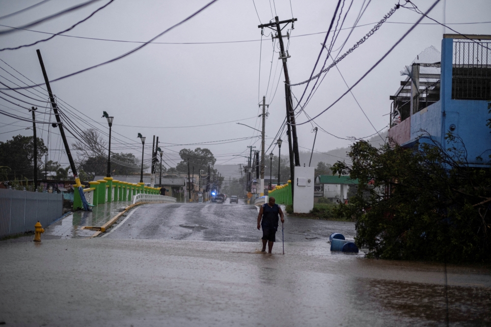 A man wades through a flooded street after Hurricane Fiona affected the area in Yauco, Puerto Rico September 18, 2022. REUTERS/Ricardo Arduengo/File Photo