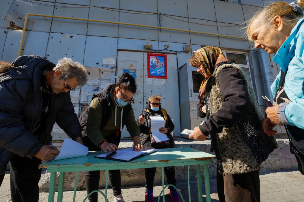 Local residents wait before receiving ballots from members of an electoral commission and casting their votes into a mobile ballot box on the third day of a referendum on the joining of the self-proclaimed Donetsk People's Republic (DPR) to Russia, in Mariupol, Ukraine on September 25, 2022. REUTERS/Alexander Ermochenko