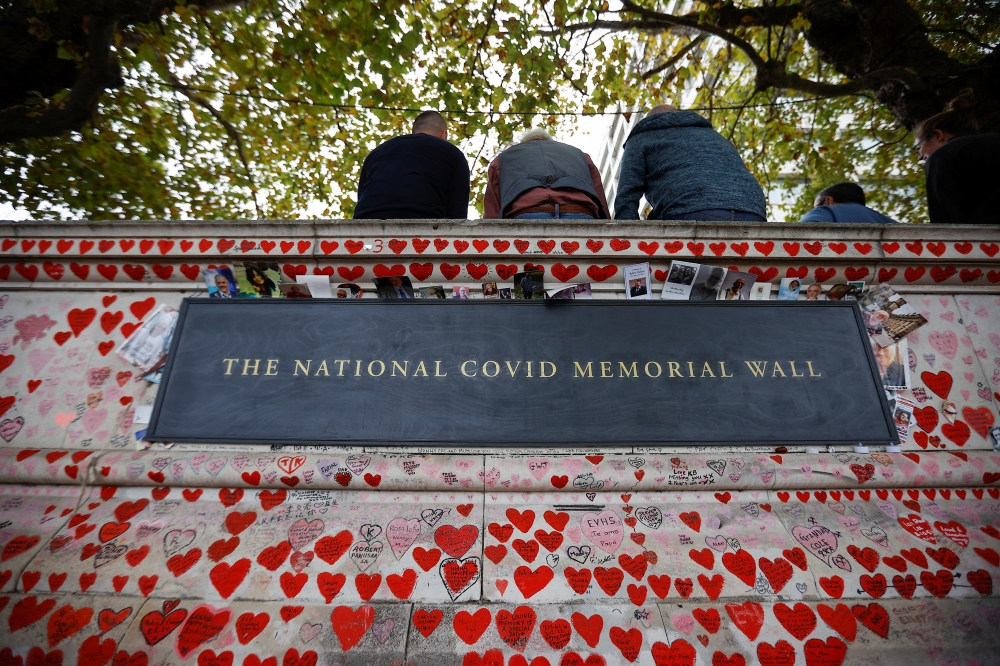 Photographs are left at the National Covid Memorial Wall, a dedication of thousands of hand painted hearts and messages commemorating victims of the Covid-19 pandemic, in London, Britain, October 4, 2022. (REUTERS/Peter Nicholls)