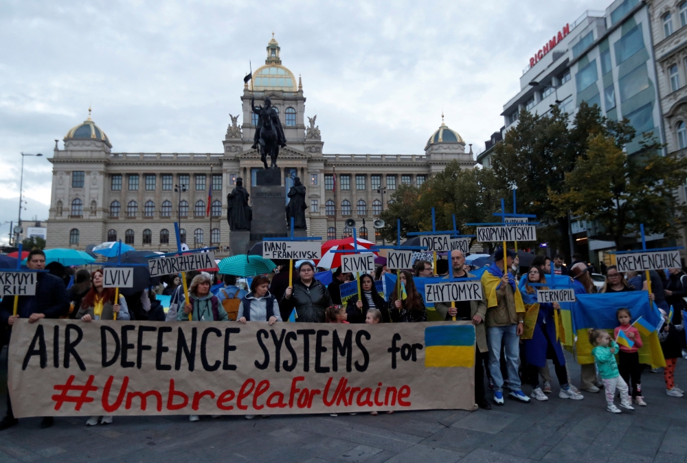 Protesters hold signs during a rally to condemn recent Russian widespread missile strikes on Ukraine, in Prague, Czech Republic, on October 10, 2022. REUTERS/David W Cerny