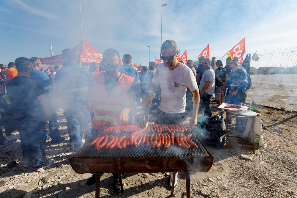 Demonstrators cook sausages during a TotalEnergies and Esso ExxonMobil workers' protest outside TotalEnergies refinery in La Mede, France, on October 11, 2022. REUTERS/Eric Gaillard