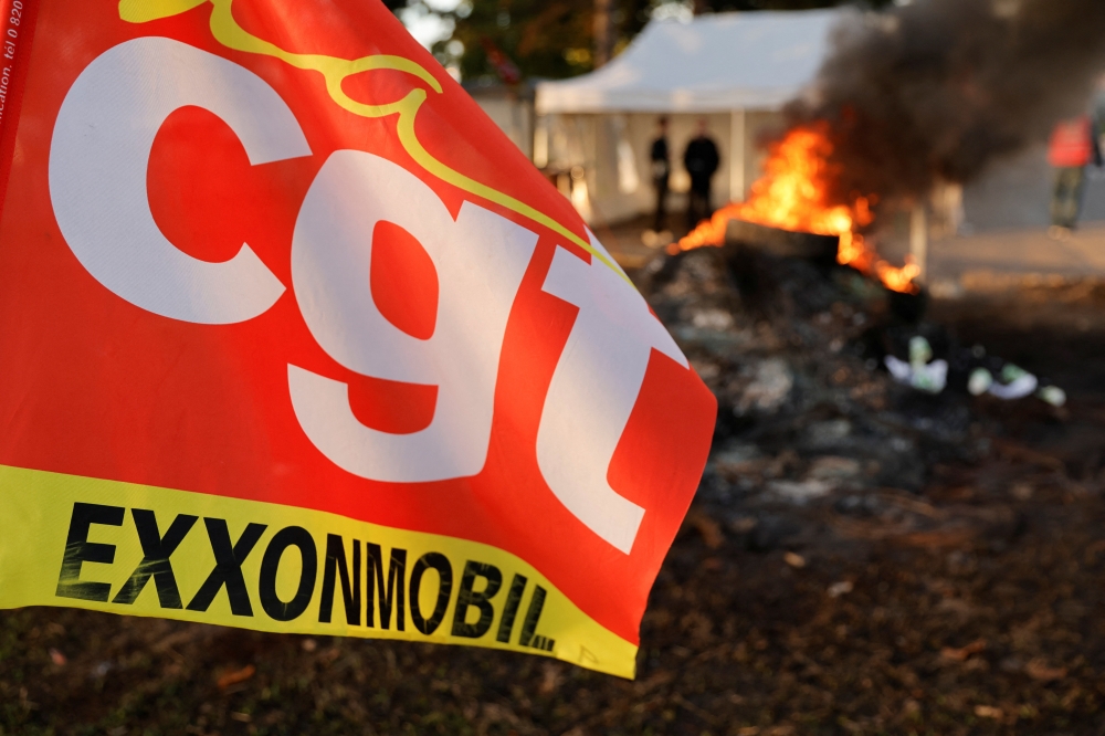 CGT trade union flag flutters as fire burns in front of the ExxonMobil oil refinery in Port-Jerome-sur-Seine, France, October 12, 2022. Reuters/Pascal Rossignol
 