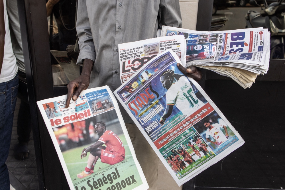 A man sells Senegalese newspapers with headlines of footballer, Sadio Mane's knee injury in Dakar on November 10, 2022. (AFP/John Wessels)