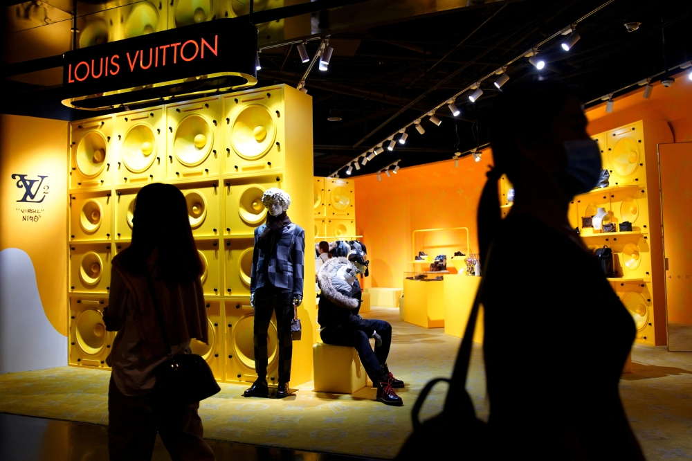 Customers wearing face masks following the COVID-19 outbreak walk past a store of French luxury brand Louis Vuitton inside a shopping mall in Beijing, China September 19, 2020. REUTERS/Tingshu Wang/File Photo/File Photo