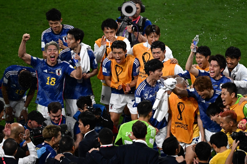 Japan's players celebrate their win in the Qatar 2022 World Cup Group E football match between Germany and Japan at the Khalifa International Stadium in Doha on November 23, 2022. (Photo by Anne-Christine POUJOULAT / AFP)