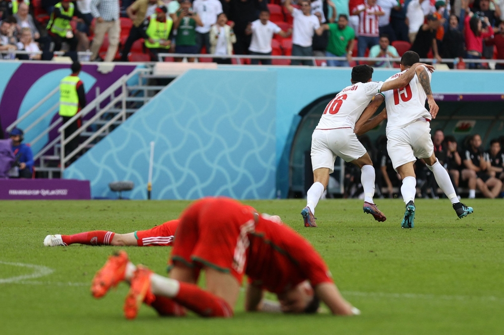 Iran's midfielder Mehdi Torabi and Iran's defender Roozbeh Cheshmi celebrate their team's victory during the Qatar 2022 World Cup Group B football match between Wales and Iran at the Ahmad Bin Ali Stadium n November 25, 2022. (Photo by ADRIAN DENNIS / AFP)