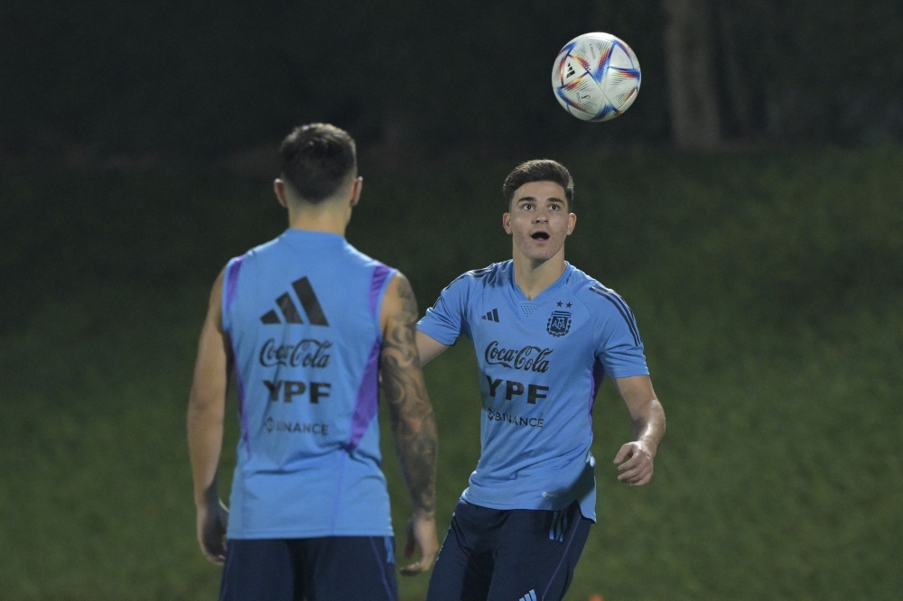 Argentina's forward Julian Alvarez (R) eyes the ball next to Argentina's defender Lisandro Martinez during a training session at Qatar University in Doha, on December 5, 2022 ahead of the Qatar 2022 World Cup quarterfinal football match against Netherlands to be held on December 9 at Lusail stadium. (Photo by JUAN MABROMATA / AFP)