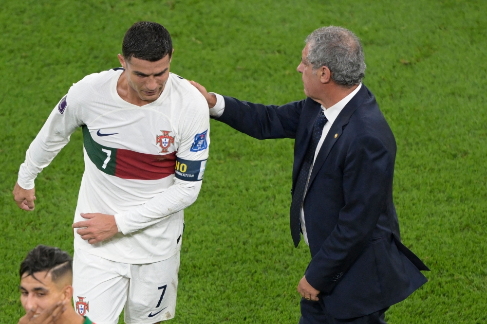 Portugal's coach Fernando Santos pats Portugal's forward Cristiano Ronaldo on his back as he leaves the field after losing to Morocco 1-0 in the Qatar 2022 World Cup quarter-final football match between Morocco and Portugal at the Al-Thumama Stadium in Doha on December 10, 2022. (Photo by JUAN MABROMATA / AFP)