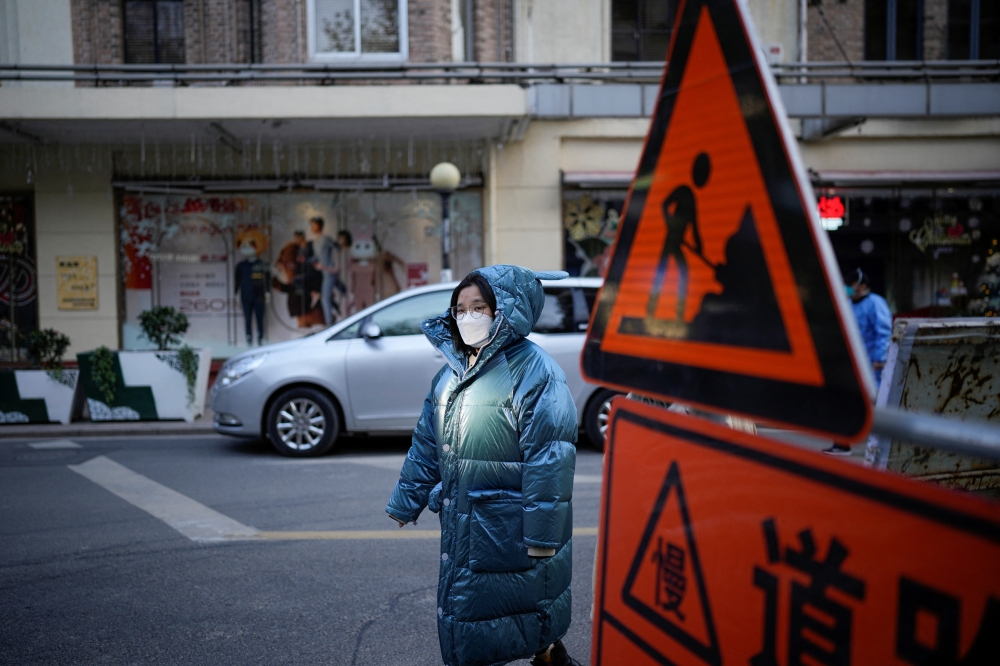 A woman wearing a face mask walks on a street, as coronavirus disease (COVID-19) outbreaks continue in Shanghai, China, December 14, 2022. REUTERS/Aly Song