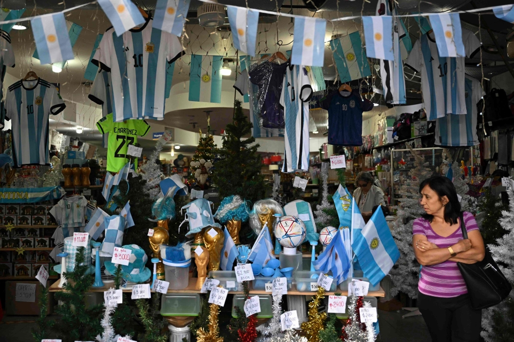 A woman walks inside a store in the eve of the Qatar 2022 World Cup final match between Argentina and France in Buenos Aires, on December 16, 2022. (Photo by Luis ROBAYO / AFP)