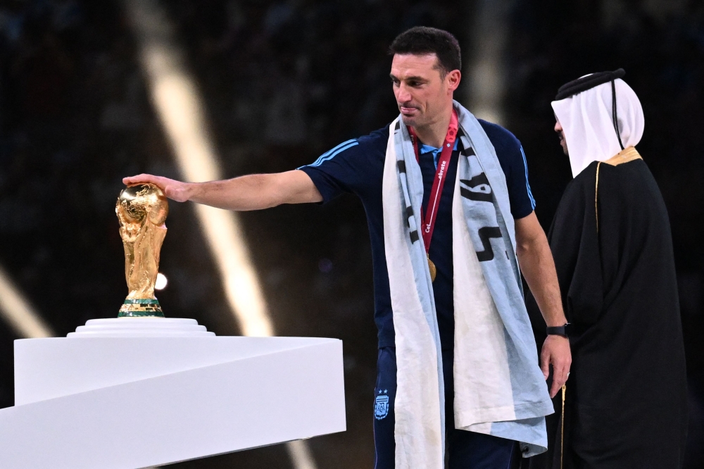 Argentina's coach Lionel Scaloni touches the FIFA World Cup Trophy during the trophy ceremony after Argentina won the Qatar 2022 World Cup final football match between Argentina and France at Lusail Stadium in Lusail, north of Doha on December 18, 2022. (Photo by Kirill KUDRYAVTSEV / AFP)
 