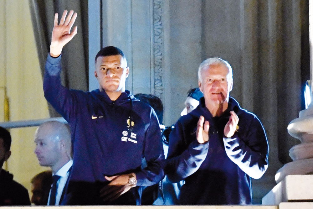 France's forward Kylian Mbappe (left) and coach Didier Deschamps greet supporters at the Hotel de Crillon, on Monday. 