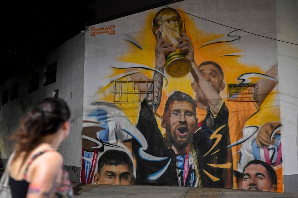 A mural by artist Maxi Bagnasco depicting Argentina's captain and forward Lionel Messi raising the FIFA World Cup Trophy next to his teammates after winning the Qatar 2022 World Cup tournament is seen in Buenos Aires on December 22, 2022. (Photo by Luis ROBAYO / AFP) 