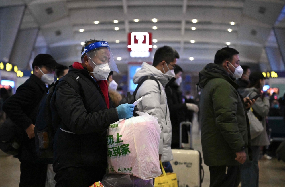 Passengers, some wearing personal protective gear to halt the spread of Covid-19, queue at a train station in Beijing on January 5, 2023. (Photo by Noel Celis / AFP)