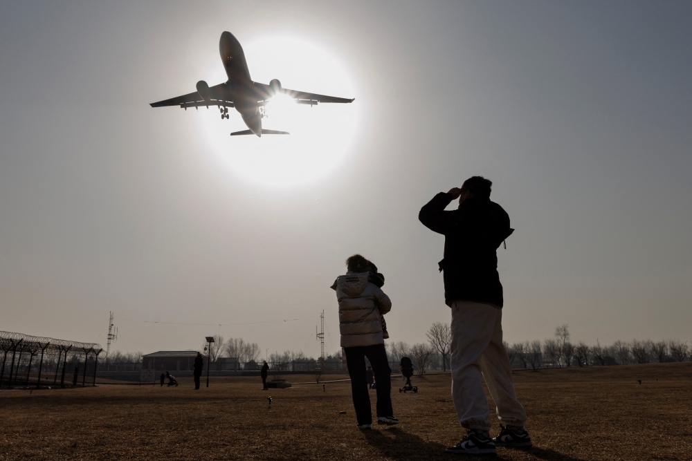 People watch a plane land at Beijing Capital International Airport as coronavirus disease (COVID-19) outbreaks continue in Beijing, China January 6, 2023. REUTERS/Thomas Peter