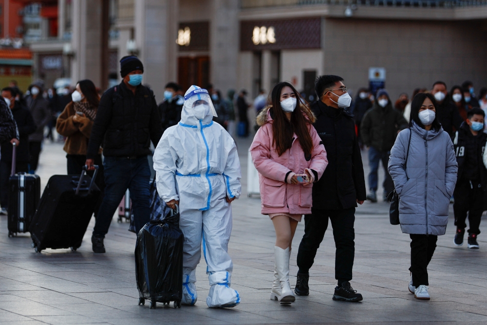 A traveller wearing a protective suit walks outside Beijing Railway Station as the annual Spring Festival travel rush starts, amid the coronavirus disease (COVID-19), ahead of the Chinese Lunar New Year, in Beijing, China, on January 7, 2023. REUTERS/Tingshu Wang