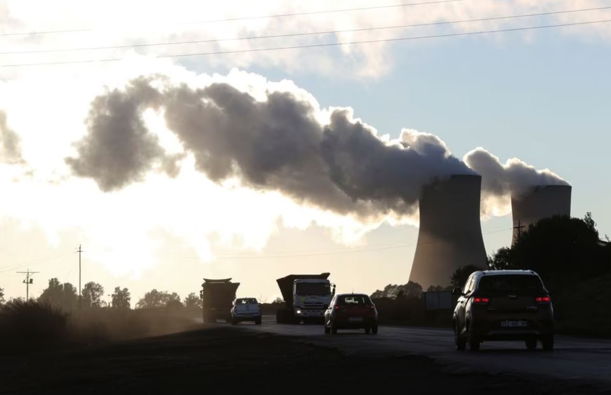 Trucks and cars are seen driving past while smoke rises from the Duvha coal-based power station owned by state power utility Eskom, in Emalahleni, in Mpumalanga province, South Africa, June 3, 2021. (REUTERS/Siphiwe Sibeko)