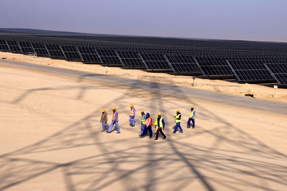 Employees walk at Al Dhafra Solar Photovoltaic (PV) Independent Power Producer (IPP) project, in the United Arab Emirates' capital Abu Dhabi, during a visit by the French economy minister on January 31, 2023. (Photo by Karim Sahib / AFP)